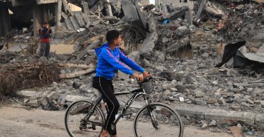 A Palestinian boy on a bicycle looks at rubble of a building following Israeli strikes in Rafah in the southern Gaza Strip, Palestine, Nov. 22, 2023. (AFP Photo)