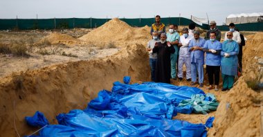 People pray as the bodies of Palestinians killed in Israeli strikes and fire are buried in a mass grave, after they were transported from Al-Shifa Hospital in Gaza City for burial, in Khan Younis, in the southern Gaza Strip, Nov. 22, 2023. (Reuters Photo)