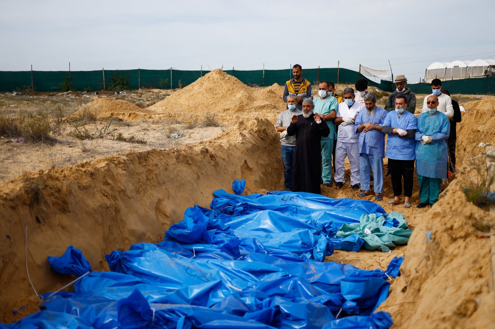 People pray as the bodies of Palestinians killed in Israeli strikes and fire are buried in a mass grave, after they were transported from Al-Shifa Hospital in Gaza City for burial, in Khan Younis, in the southern Gaza Strip, Nov. 22, 2023. (Reuters Photo)