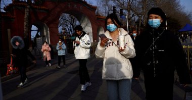 People, wearing masks, walk along the street in Beijing, China, Feb. 14, 2023. (Reuters File Photo)