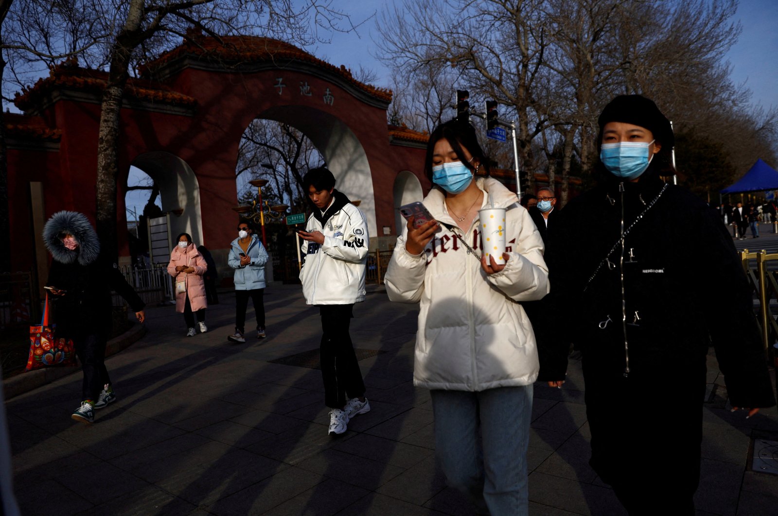 People, wearing masks, walk along the street in Beijing, China, Feb. 14, 2023. (Reuters File Photo)