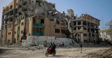 Palestinians drive a motorcycle past the destroyed building of the Islamic University in Gaza City, Palestine, Nov. 26, 2023. (AFP Photo)