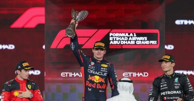 Ferrari's Monegasque driver Charles Leclerc (L) and Mercedes' British driver George Russell (R) watch as Red Bull Racing's Dutch driver Max Verstappen celebrates with the winner's trophy on the podium after the Abu Dhabi Formula One Grand Prix at the Yas Marina Circuit, Abu Dhabi, UAE, Nov. 26, 2023. (AFP Photo)