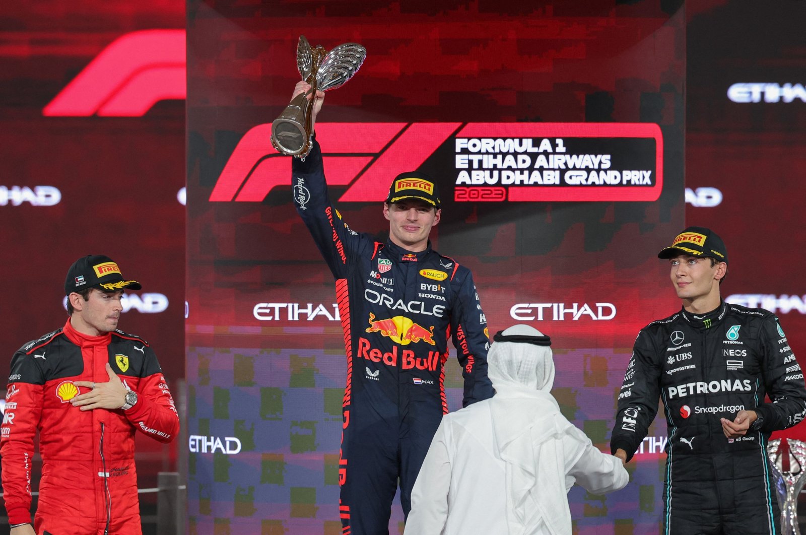 Ferrari&#039;s Monegasque driver Charles Leclerc (L) and Mercedes&#039; British driver George Russell (R) watch as Red Bull Racing&#039;s Dutch driver Max Verstappen celebrates with the winner&#039;s trophy on the podium after the Abu Dhabi Formula One Grand Prix at the Yas Marina Circuit, Abu Dhabi, UAE, Nov. 26, 2023. (AFP Photo)