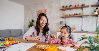 A young mother playing with her child at the kitchen table with toys, April 4, 2023. (Getty Images Photo)