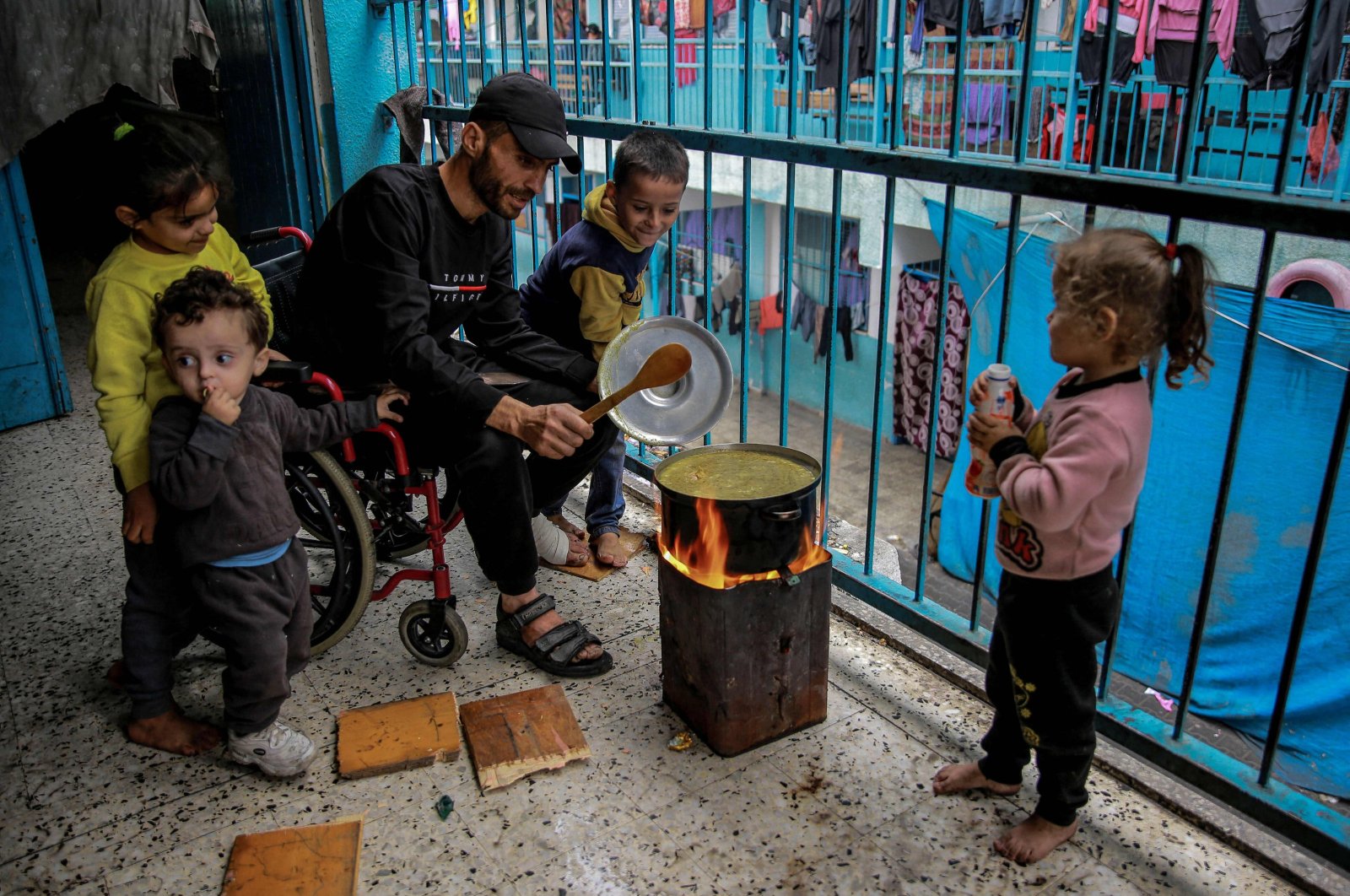 A Palestinian man surrounded by children cooks at a U.N. Palestinian refugee agency (UNRWA) school used as a shelter on the fourth day of a truce in fighting between Israel and Palestine, in Gaza City, Palestine, Nov. 27, 2023. (AFP Photo)