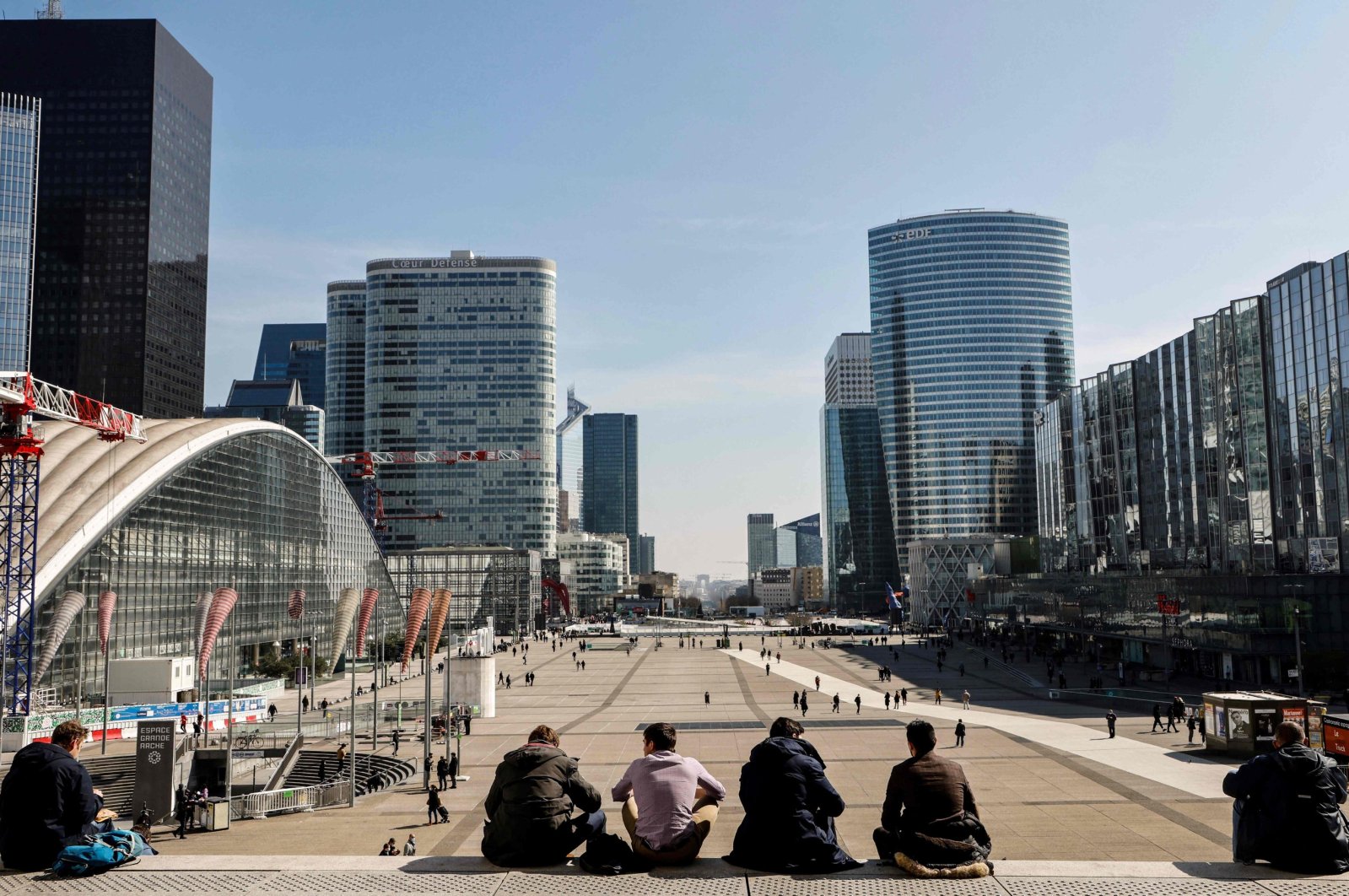 People sit on stairs on the Parvis de la Defense in Paris&#039; business district of La Defense, outside Paris, March 23, 2021. (AFP Photo)