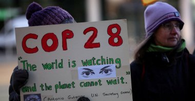 A climate activist holds a placard during a vigil to mark the opening day of the COP28 summit outside the offices of the BBC in Salford, Britain, Nov. 30, 2023. (Reuters Photo)