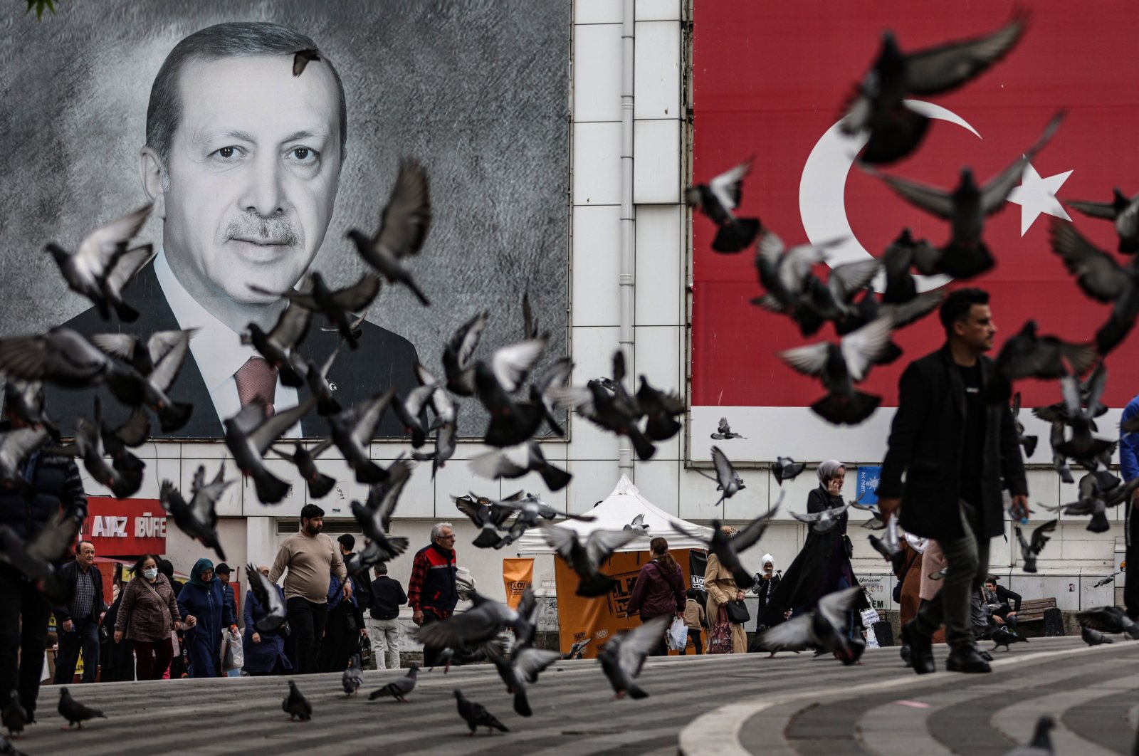 People pass a portrait of President Recep Tayyip Erdoğan and a Turkish flag ahead of general elections, in northwestern Bursa province, Türkiye, May 11, 2023. (EPA Photo)