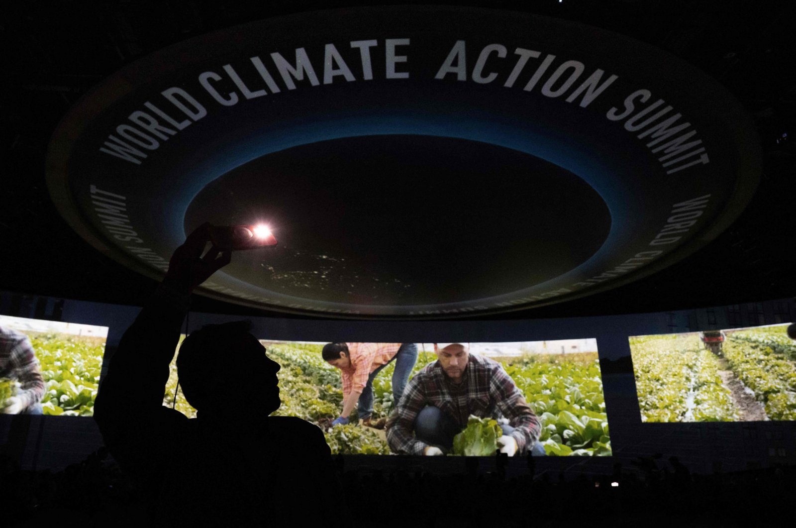 An attendee takes photos during a video presentation as part of the Transforming Food Systems in the Face of Climate Change event on the sidelines of the COP28 climate summit at Dubai Expo, United Arab Emirates, Dec. 1, 2023. (AFP Photo)