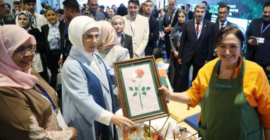Türkiye’s first lady Emine Erdoğan poses with a paper marbling portrait made by a climate volunteer as she visits the Türkiye Pavilion at the Expo City Dubai, United Arab Emirates, Dec. 1, 2023. (AA Photo)