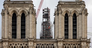 Workers place the cross atop the newly rebuilt spire, as they stand on scaffolding, during reconstruction work, at Notre-Dame de Paris Cathedral, Paris, France, Dec. 6, 2023. (AFP Photo)