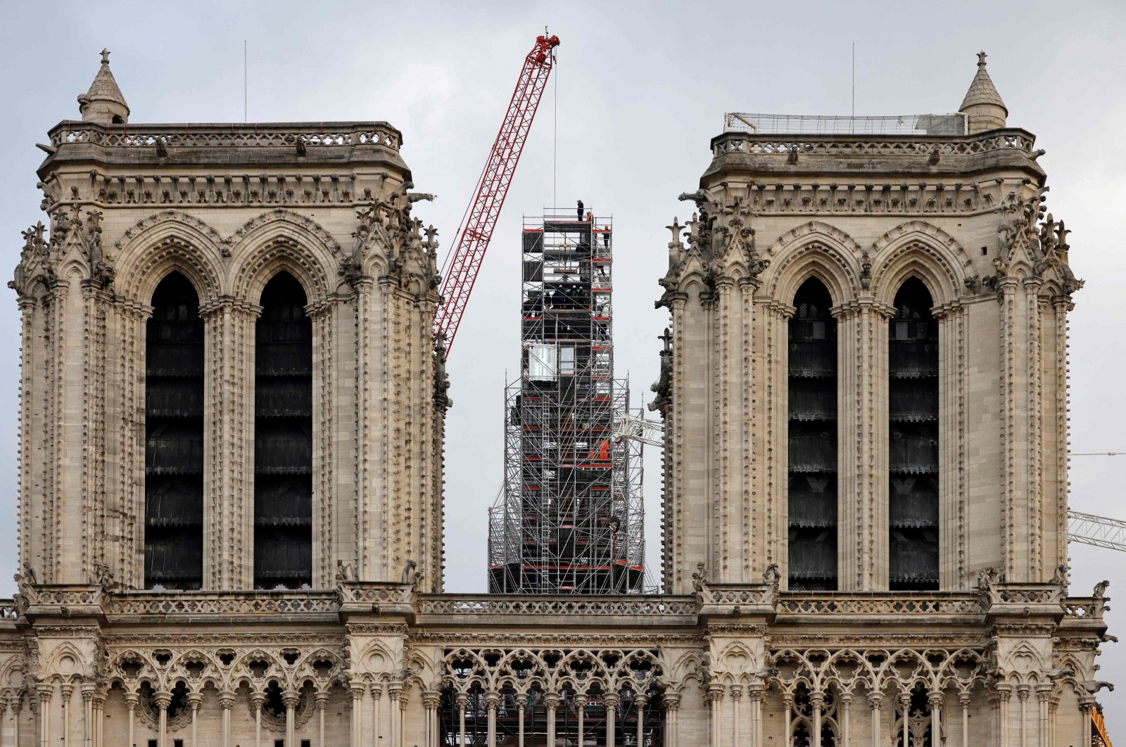 Workers place the cross atop the newly rebuilt spire, as they stand on scaffolding, during reconstruction work, at Notre-Dame de Paris Cathedral, Paris, France, Dec. 6, 2023. (AFP Photo)