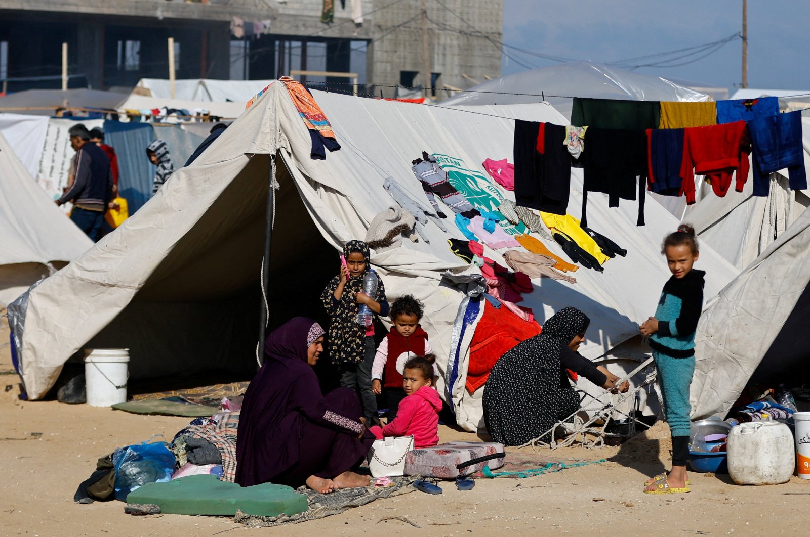 A woman sits with children outside, as displaced Palestinians, who fled their houses due to Israeli strike, shelter in a camp in Rafah, in the southern Gaza Strip, Palestine, Dec. 6, 2023. (Reuters Photo)