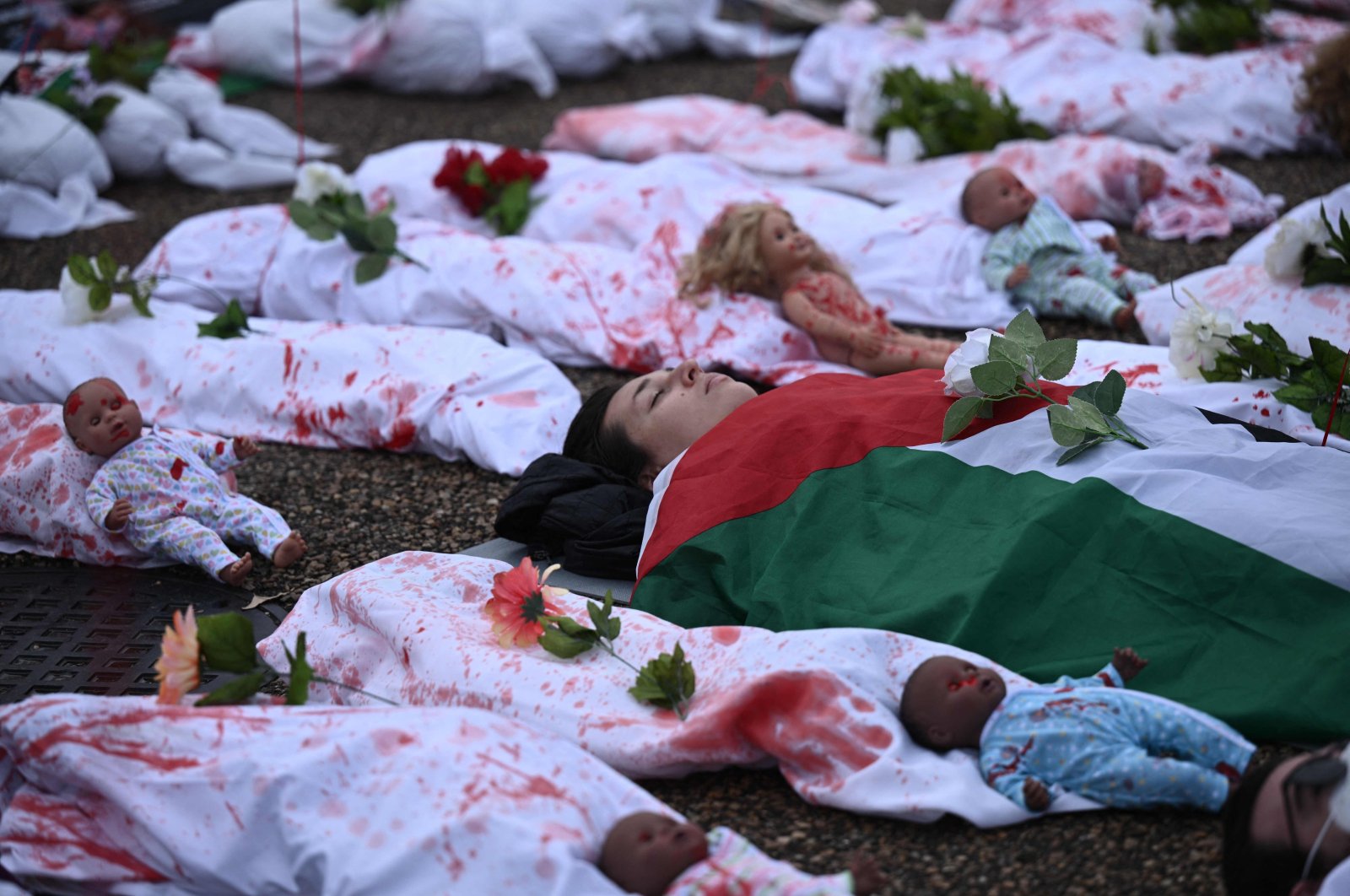 Activists representing victims in the Israel-Palestine conflict, lay on the ground in front of the White House during a rally in support of Palestinians in Washington, DC, Dec. 2, 2023. (AFP Photo)