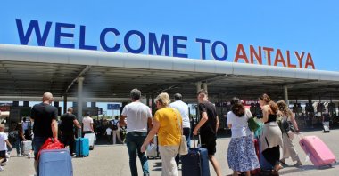 Tourists are photographed in front of the entrance to Antalya Airport in southern Türkiye, Dec. 6, 2023. (IHA Photo)