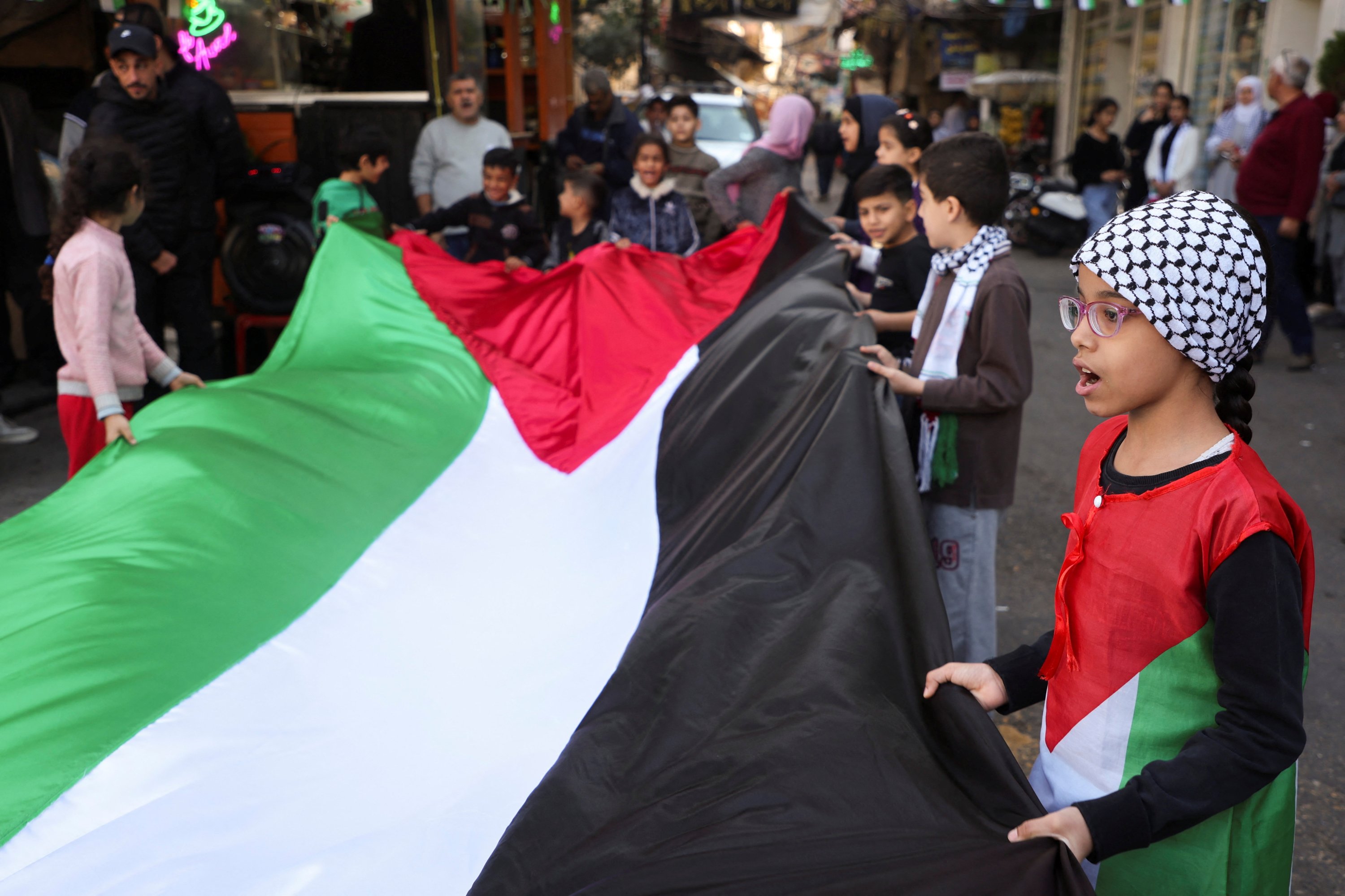 Children hold a Palestinian flag during a sit-in, in response to the global call for a strike in solidarity with Gaza, Burj al-Barajneh refugee camp, Beirut, Lebanon, Dec. 11, 2023. (Reuters Photo)