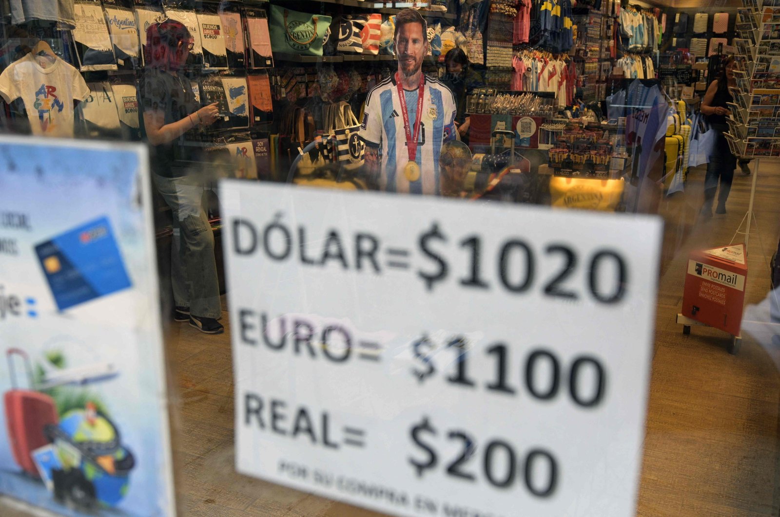 An image of Argentina&#039;s forward Lionel Messi is seen at a store displaying a sign with the exchange rate for U.S. dollars, euros and Brazilian reales in Argentine pesos, in Buenos Aires, Argentina, Nov. 21, 2023. (AFP Photo)