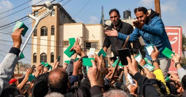 Palestinians wave their identity cards as they gather to receive flour rations for their families outside a U.N. warehouse, Rafah, Gaza Strip, Palestine, Dec. 12, 2023. (AFP Photo)