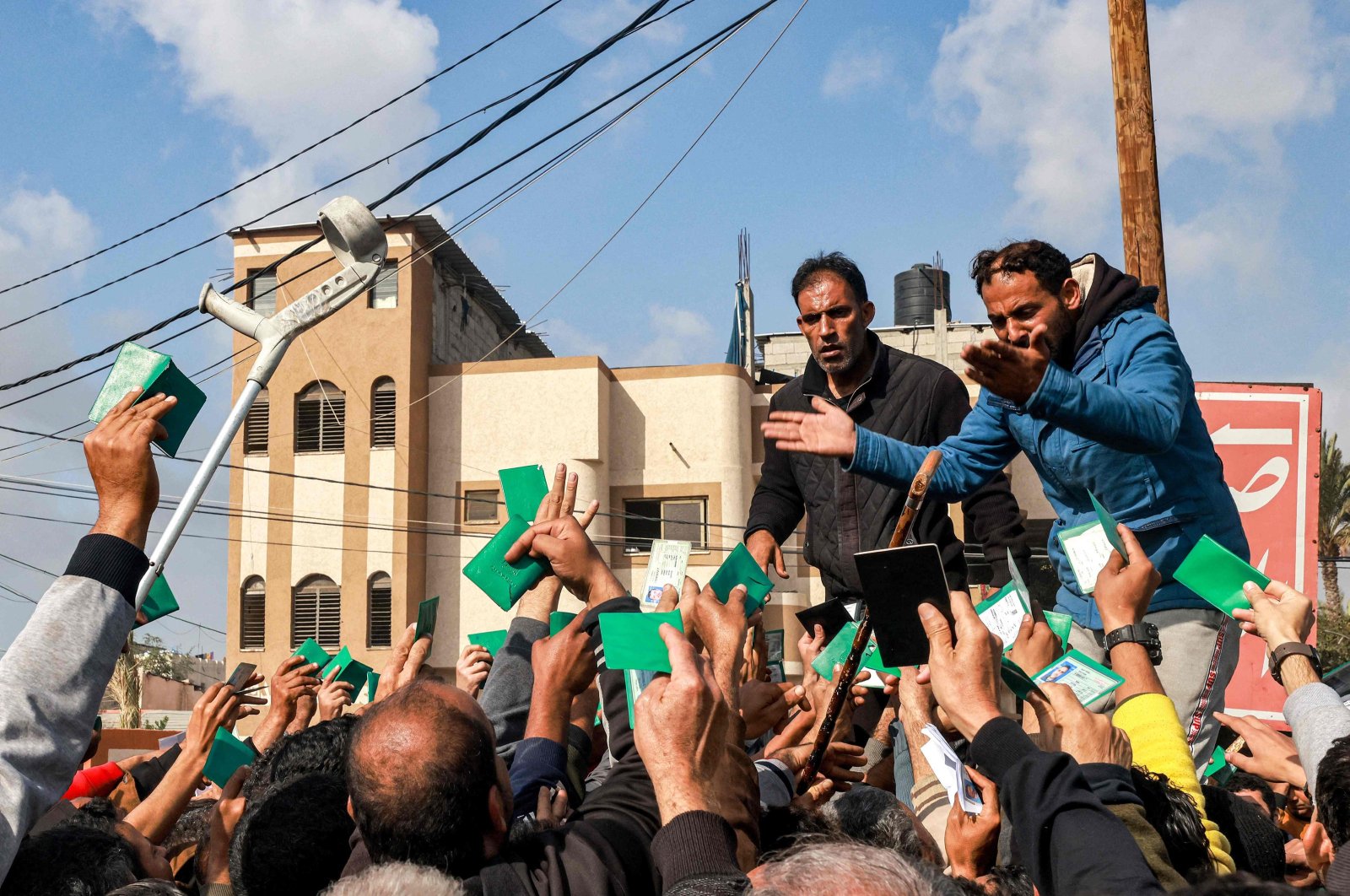 Palestinians wave their identity cards as they gather to receive flour rations for their families outside a U.N. warehouse, Rafah, Gaza Strip, Palestine, Dec. 12, 2023. (AFP Photo)
