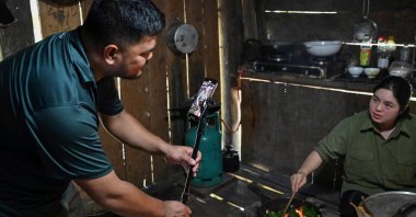 TikToker and farmer Luong Quang Dai uses a mobile phone to shoot a video of his wife cooking for a TikTok video at his house in Bac Kan province, Vietnam, Oct. 17, 2023. (AFP Photo)