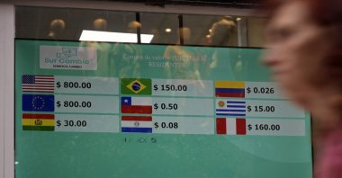 A woman walks by a currency exchange office displaying a screen with the exchange rate for U.S. dollars, euros, and other Latin American currencies in Argentine pesos, in Buenos Aires, Argentina, Nov. 21, 2023. (AFP Photo)