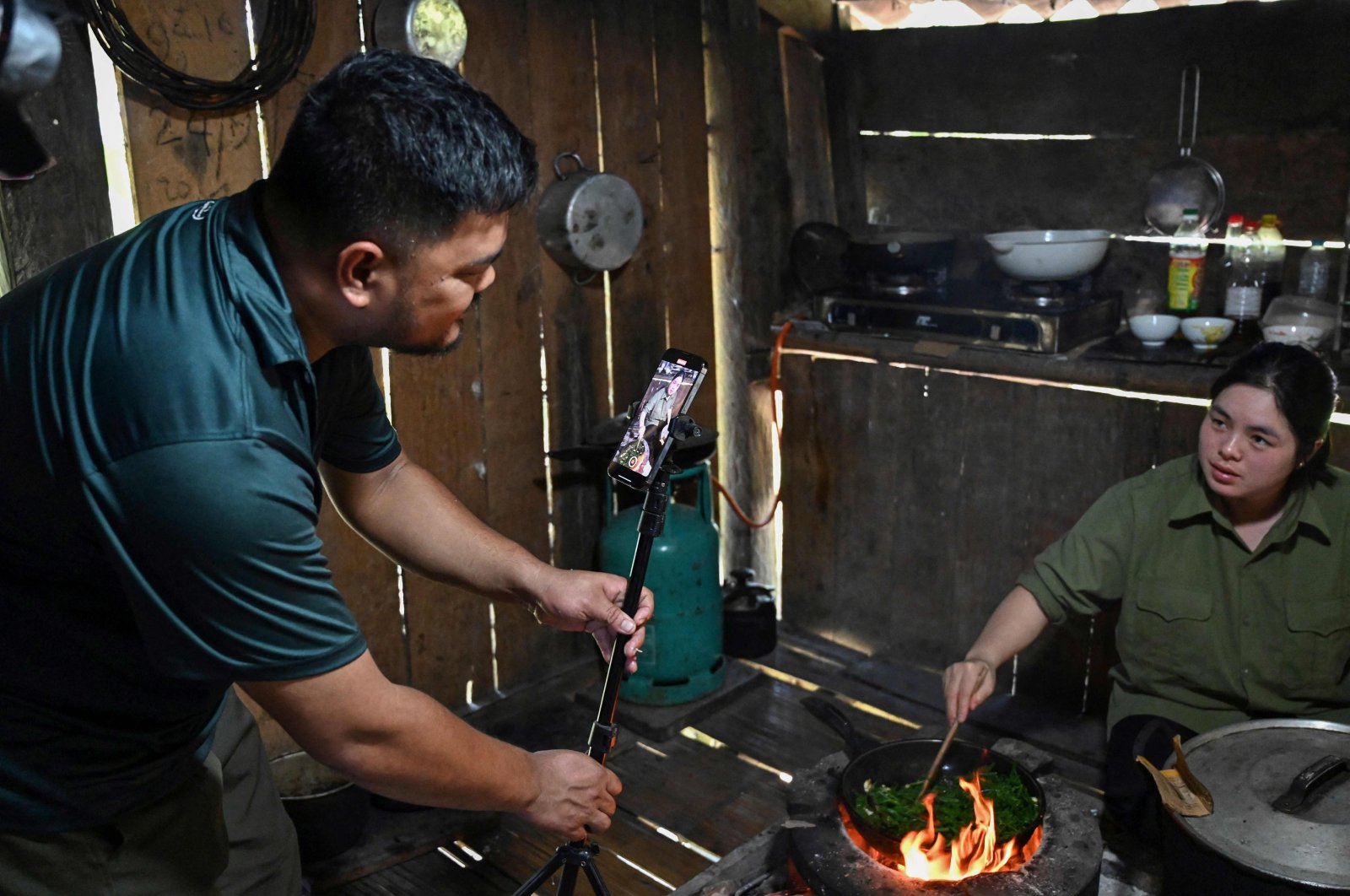 TikToker and farmer Luong Quang Dai uses a mobile phone to shoot a video of his wife cooking for a TikTok video at his house in Bac Kan province, Vietnam, Oct. 17, 2023. (AFP Photo)
