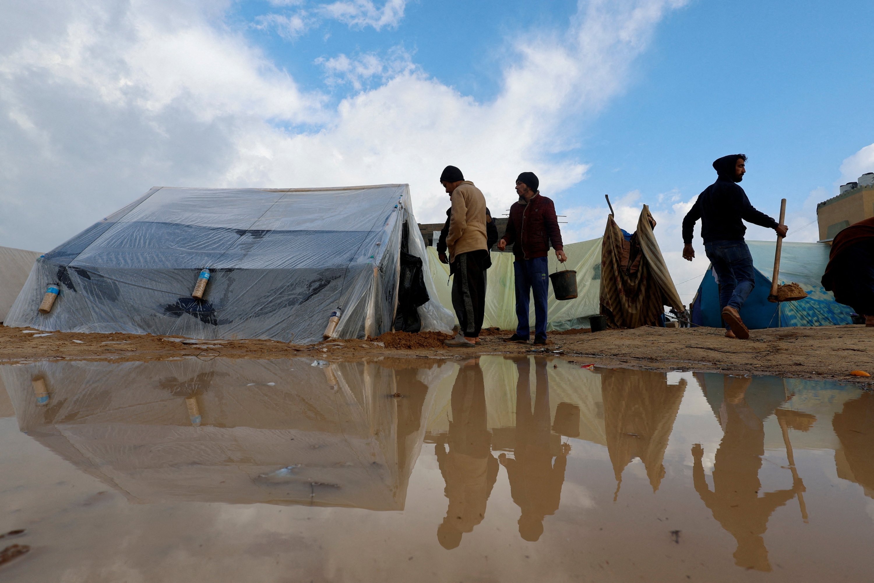 Displaced Palestinians walk next to tents following heavy rains, Rafah, southern Gaza Strip, Dec. 13, 2023. (Reuters Photo)