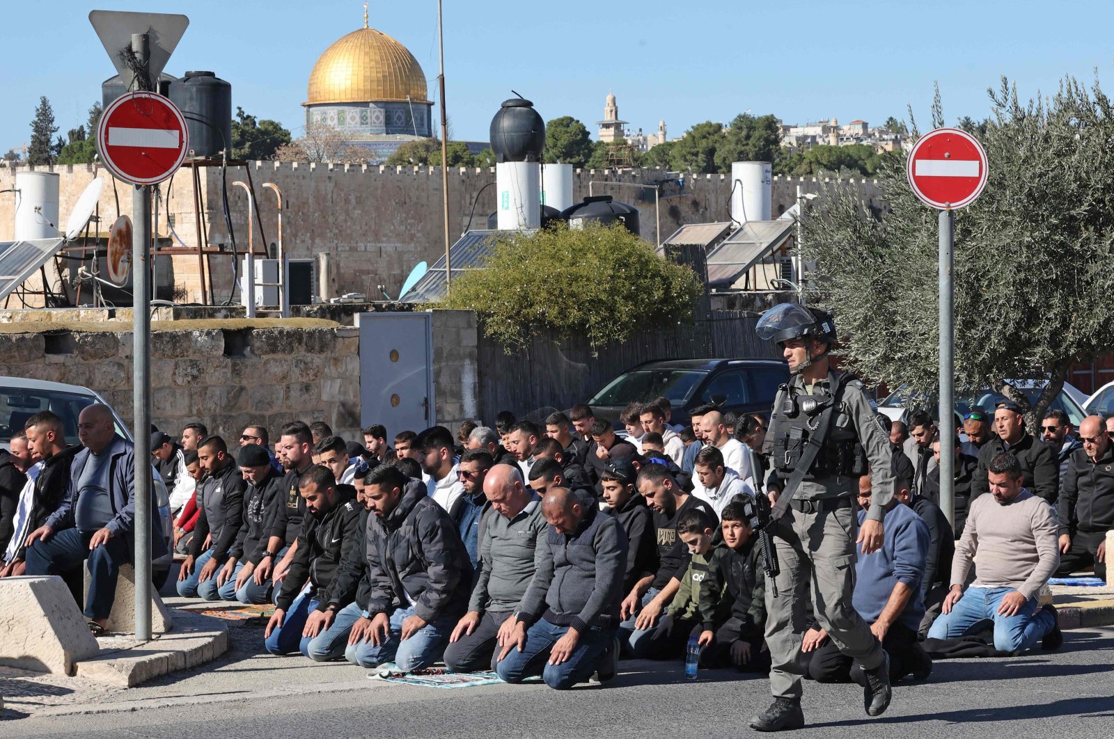Israeli security forces patrol as Palestinian Muslims perform the Friday noon prayer on a street, eastern Jerusalem, occupied Palestine, Dec.15, 2023. (AFP Photo)