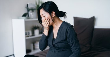 A young pregnant woman sitting on her bed, feeling nauseous and covering her mouth, suffering from morning sickness in this undated file photo. (Getty Images)