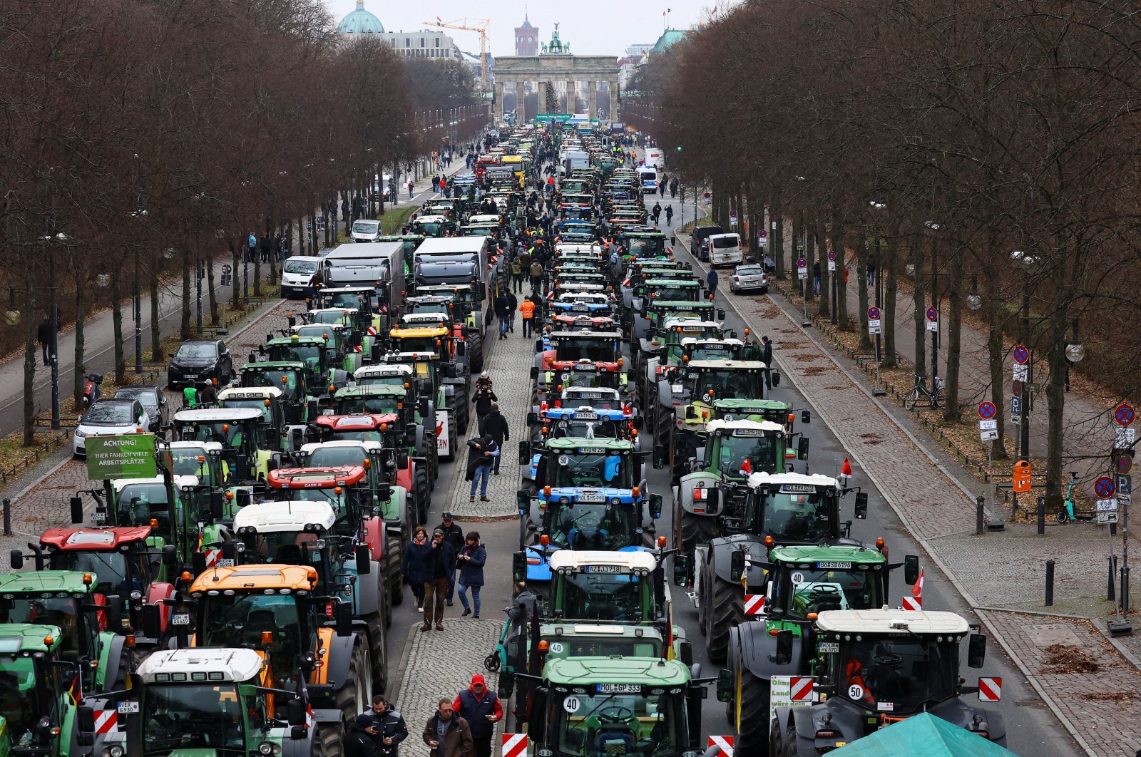 People walk beside tractors, as German farmers take part in a protest against the cut of vehicle tax subsidies, near the Brandenburg Gate in Berlin, Germany, Dec. 18, 2023. (Reuters Photo)