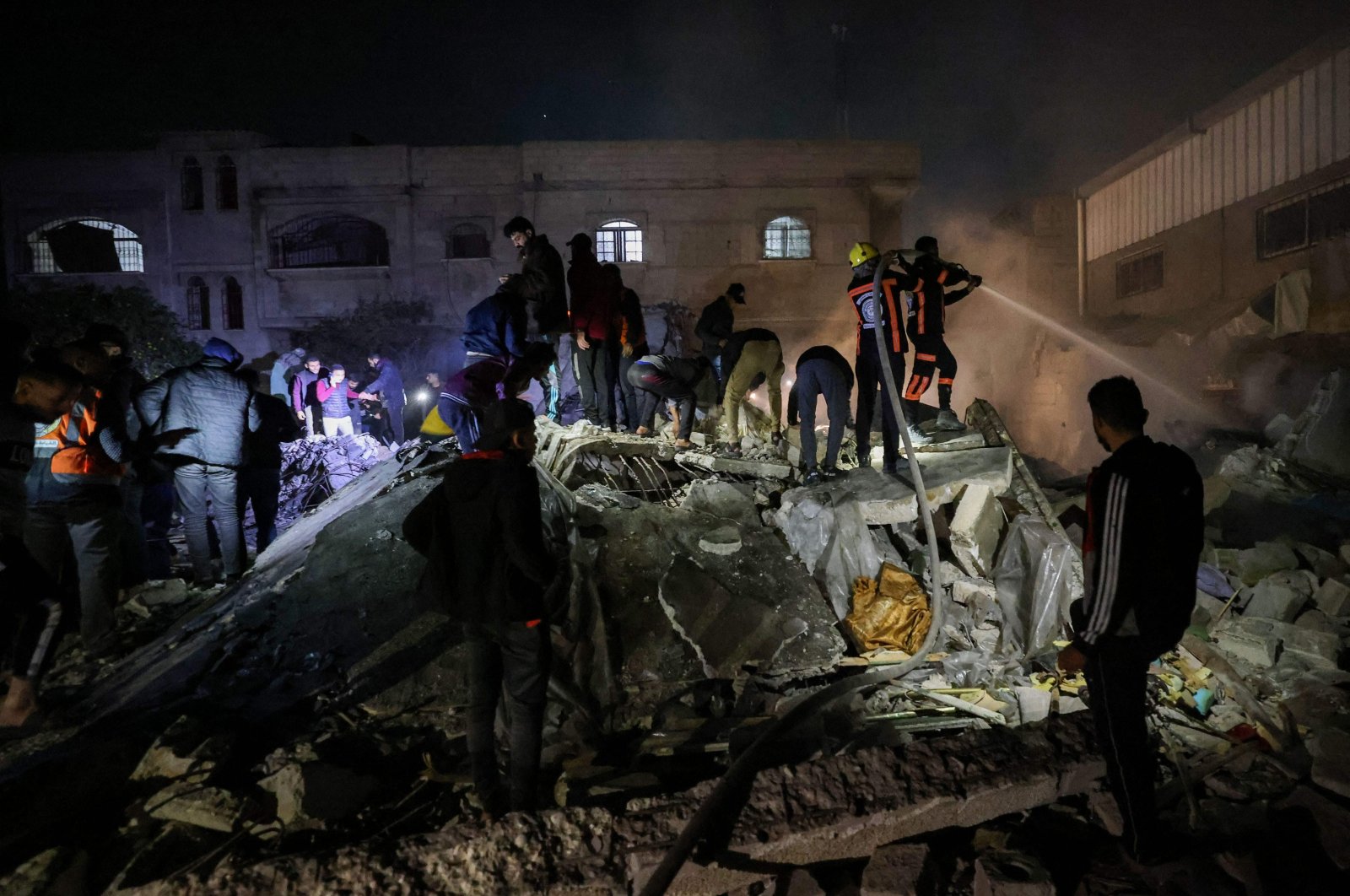 Firefighters and civilians gather at the rubble of a building following Israeli bombardment in Rafah, southern Gaza Strip, Palestine, Dec. 18, 2023. (AFP Photo)