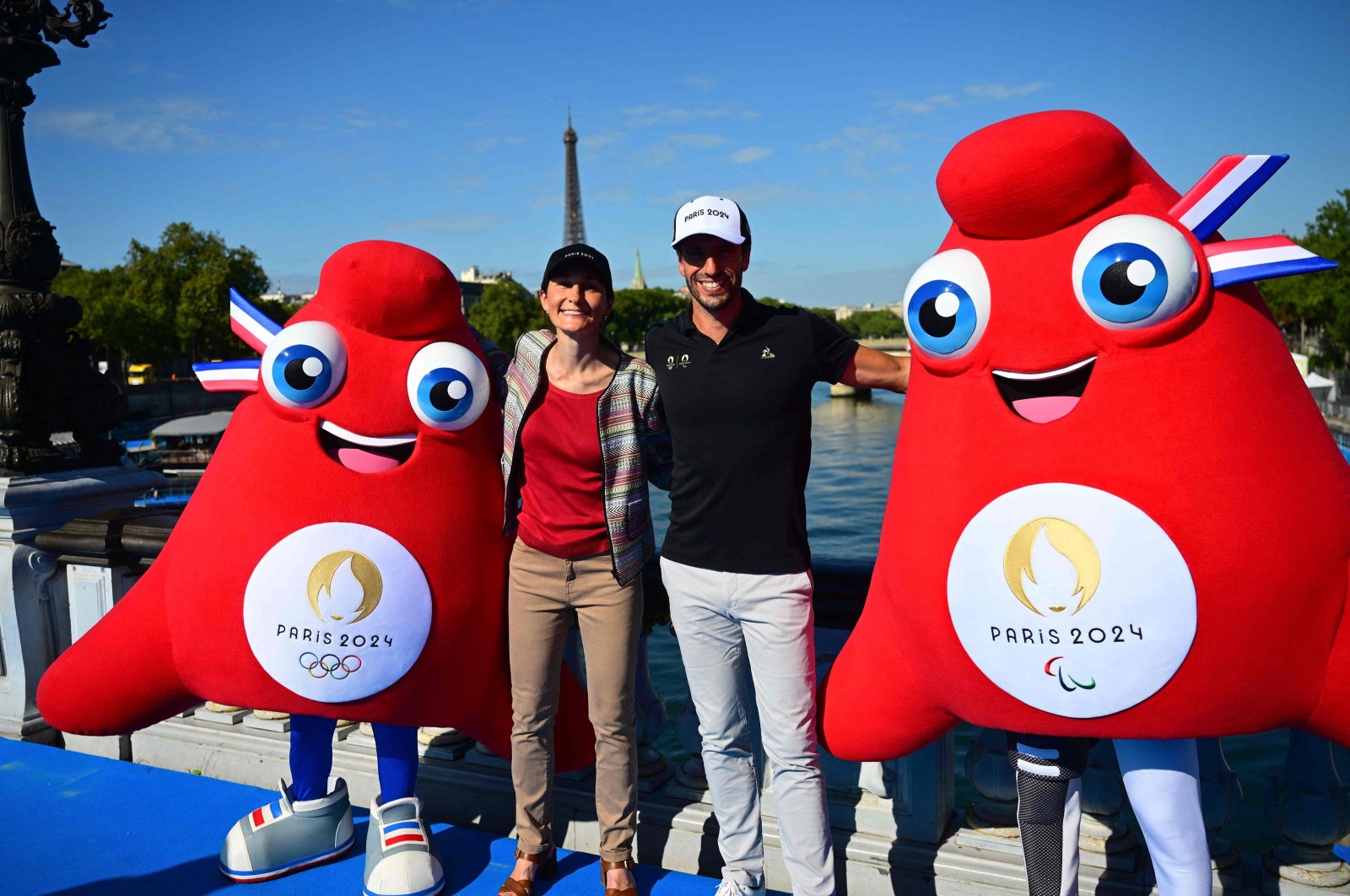 Olympic Phryges mascots pose for a photograph with French Sports Minister Amelie Oudea-Castera (L) and Paris 2024 Olympics President Tony Estanguet on the Alexandre III bridge with the Eiffel Tower in the background after the mixed relay and last day of the 2023 World Triathlon-duathlon format of the Olympic Games Test Event, Paris, France, Aug. 20, 2023. (AFP Photo)