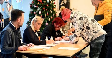 Voters (R) register in before casting their ballot at a polling station during parliamentary and local elections in Serbia, Belgrade, Dec. 17, 2023. (AFP Photo)