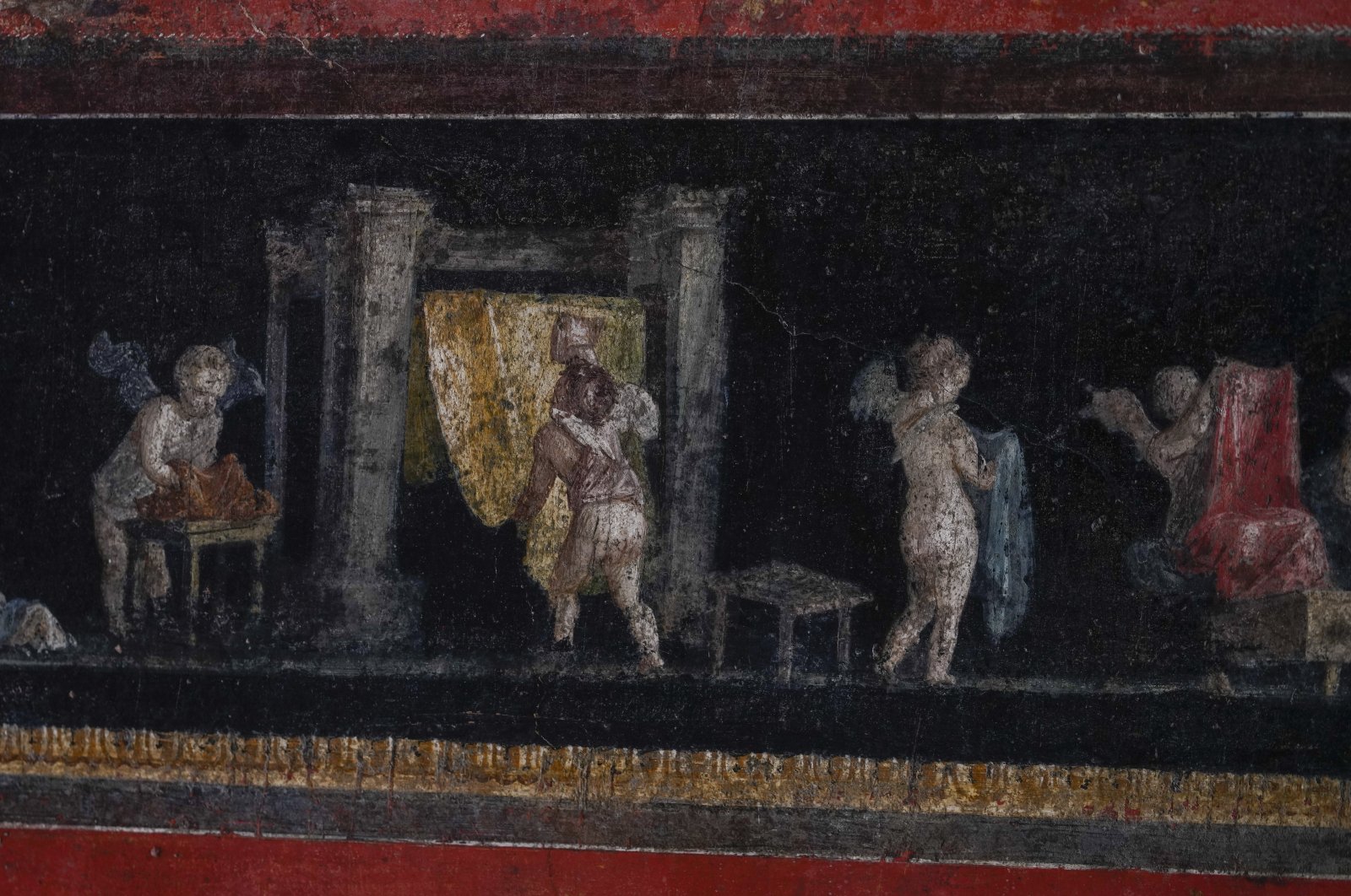 Busy winged cupids dyeing textiles are painted on a frieze at waist level that runs around the living room in one of the wealthiest homes in Pompeii, the House of the Vetti., in Pompeii, Italy, Dec. 7, 2023. (AP Photo)