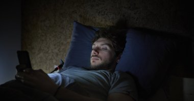 A man is using a phone late at night amid lack of sleep. (Getty images)