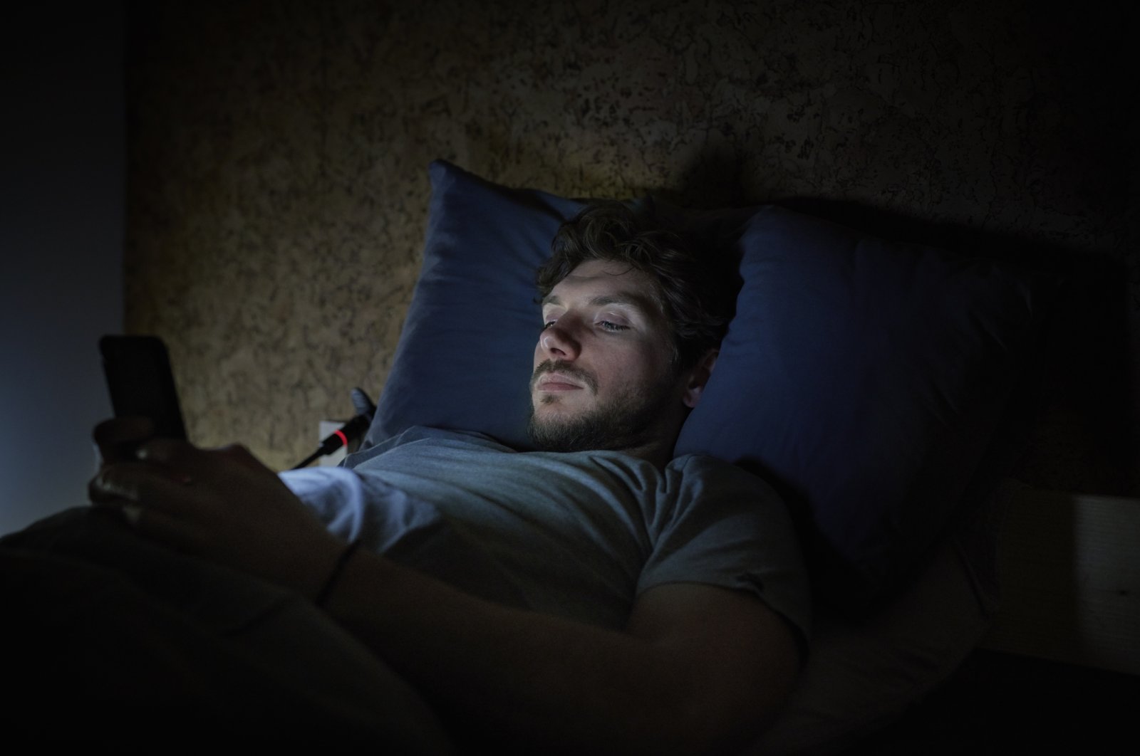 A man is using a phone late at night amid lack of sleep. (Getty images)