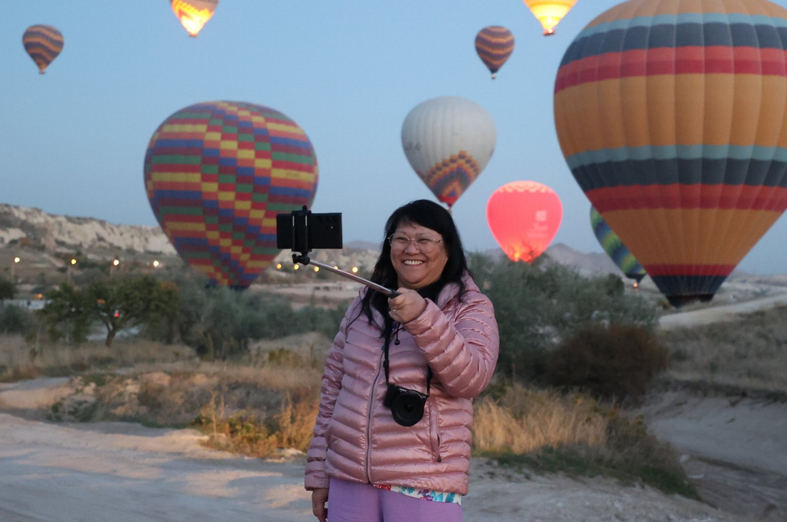A Chinese tourist takes a selfie with hot balloons in the background in famed Cappadocia, Nevşehir, central Türkiye, Dec. 12, 2023. (AA Photo)