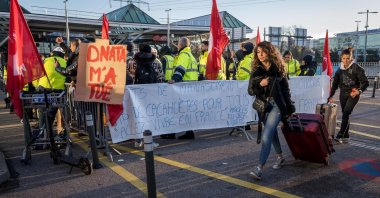Traveller walk by a picket line outside Geneva International Airport, after dozens of ground staff went on strike over a wage dispute with their employer, the Dubai National Air Travel Agency (Dnata) delaying flights during the busy holiday season, in Geneva, Switzerland, Dec. 24, 2023. (AFP Photo)