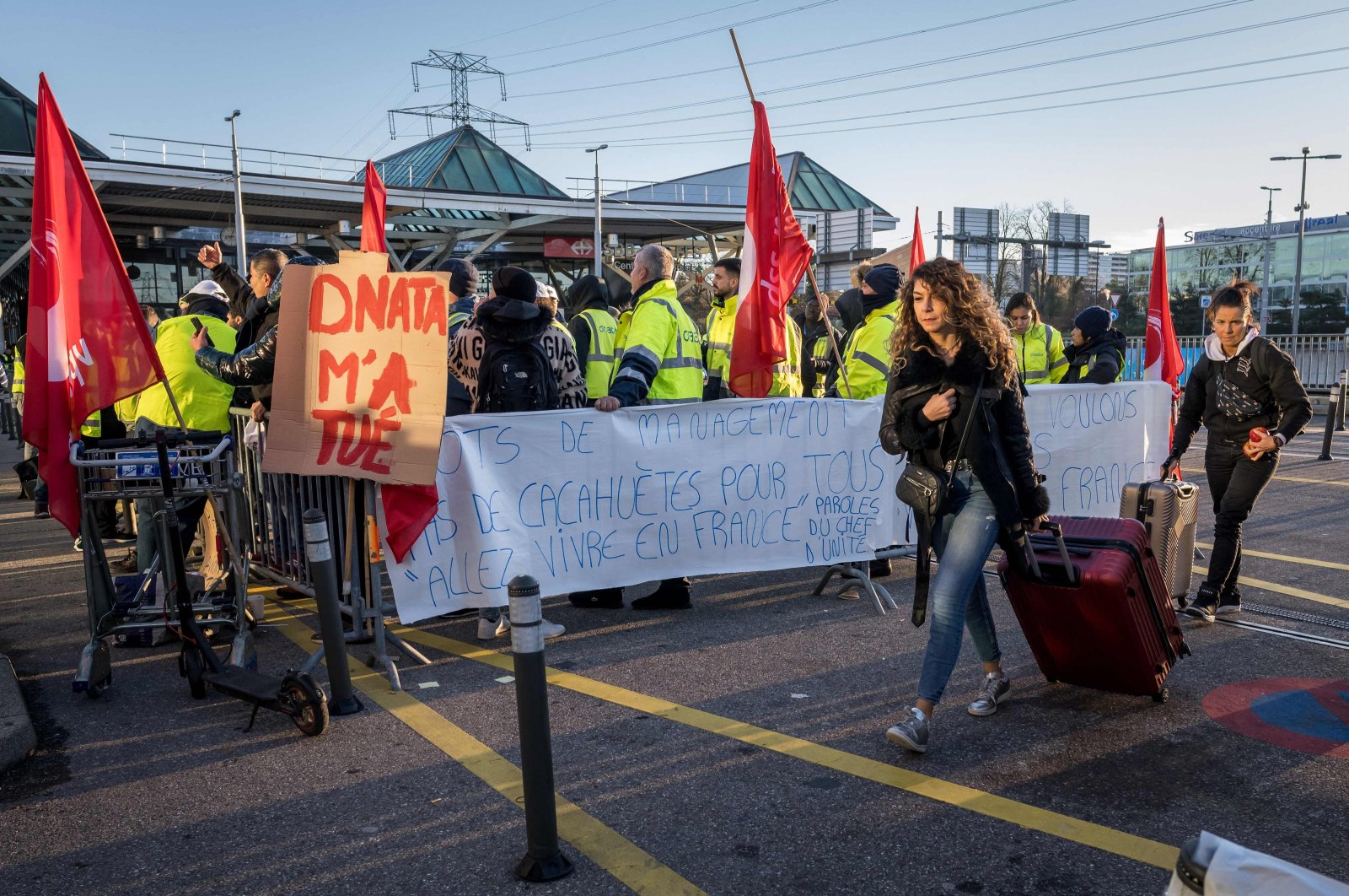 Traveller walk by a picket line outside Geneva International Airport, after dozens of ground staff went on strike over a wage dispute with their employer, the Dubai National Air Travel Agency (Dnata) delaying flights during the busy holiday season, in Geneva, Switzerland, Dec. 24, 2023. (AFP Photo)