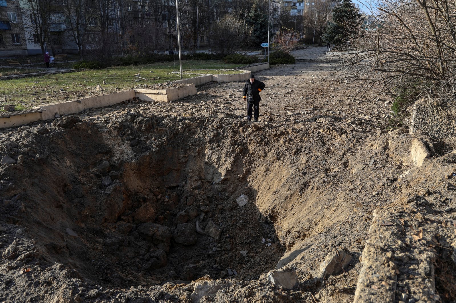 This file photo shows a local resident near a crater caused by a Russian missile strike in Kherson, Ukraine, Dec. 5, 2023. (Reuters Photo)