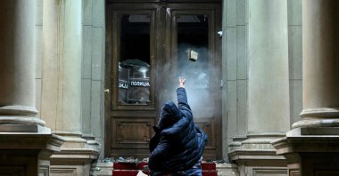 A protester throws a projectile toward police officers using pepper spray inside the Belgrade's city council building during a demonstration in Belgrade, Serbia, Dec. 24, 2023. (AFP Photo)