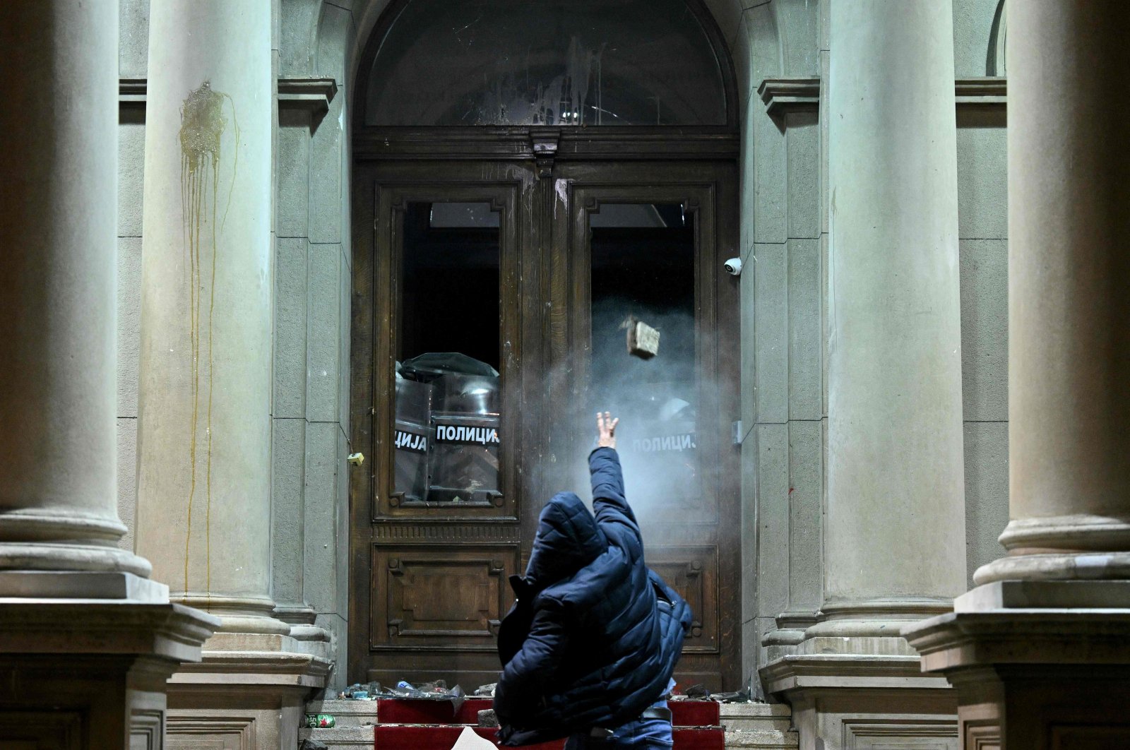 A protester throws a projectile toward police officers using pepper spray inside the Belgrade&#039;s city council building during a demonstration in Belgrade, Serbia, Dec. 24, 2023. (AFP Photo)