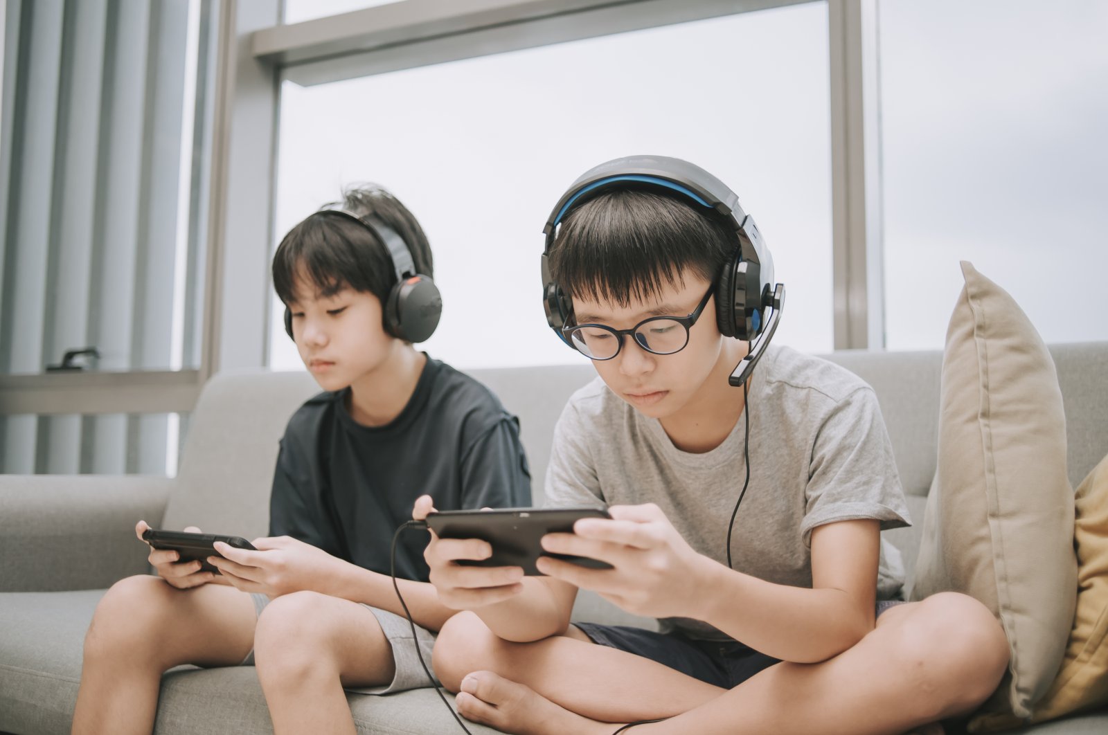 Two children playing multiplayer online games with headsets using smartphones, Dec. 9, 2020. (Getty Images Photo)