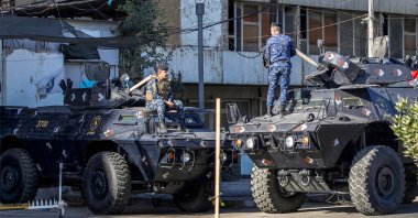Iraqi security personnel talk to each other while positioned above armored vehicles in Baghdad, Iraq, Dec. 26, 2023. (AFP Photo)