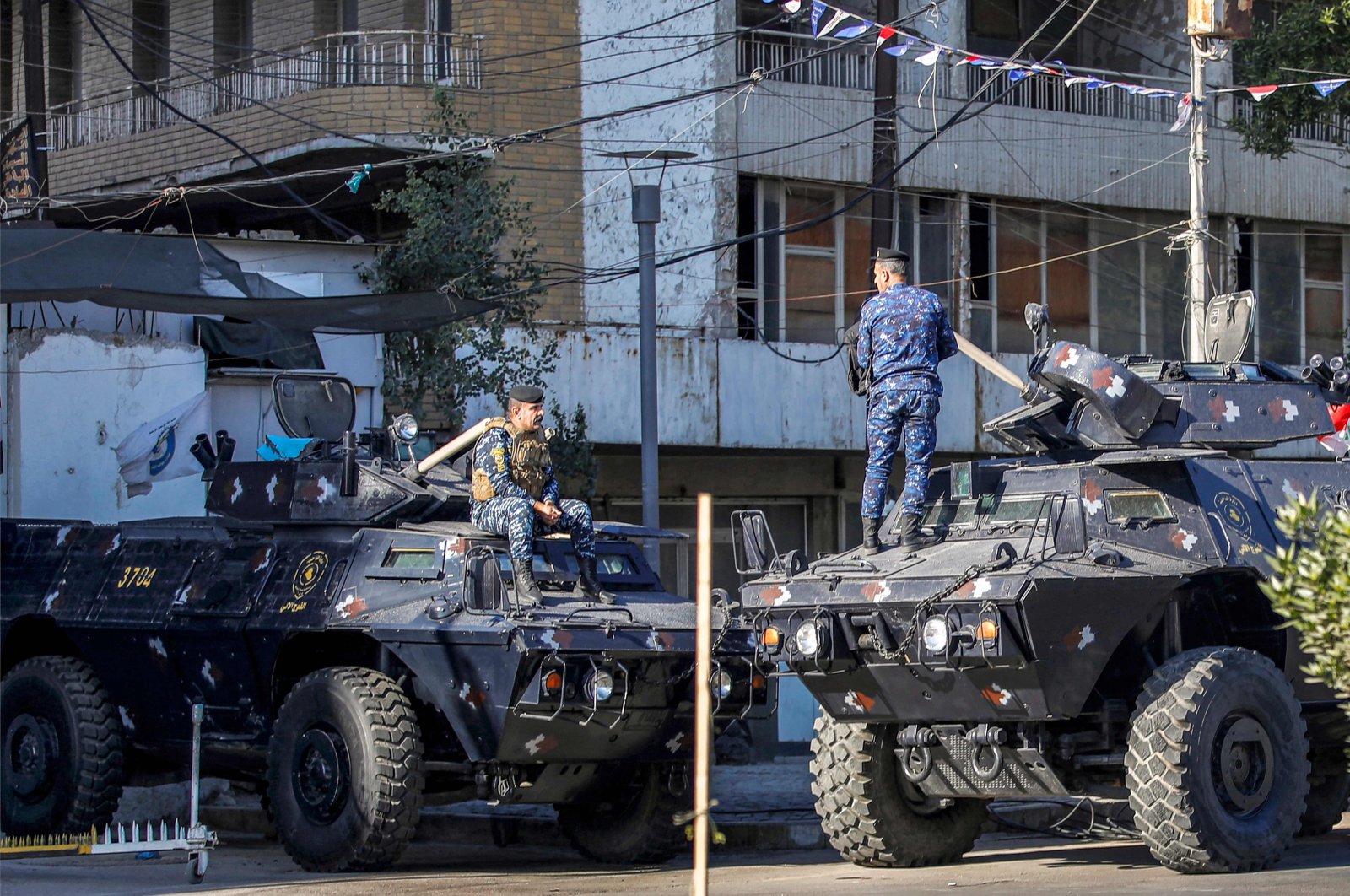 Iraqi security personnel talk to each other while positioned above armored vehicles in Baghdad, Iraq, Dec. 26, 2023. (AFP Photo)