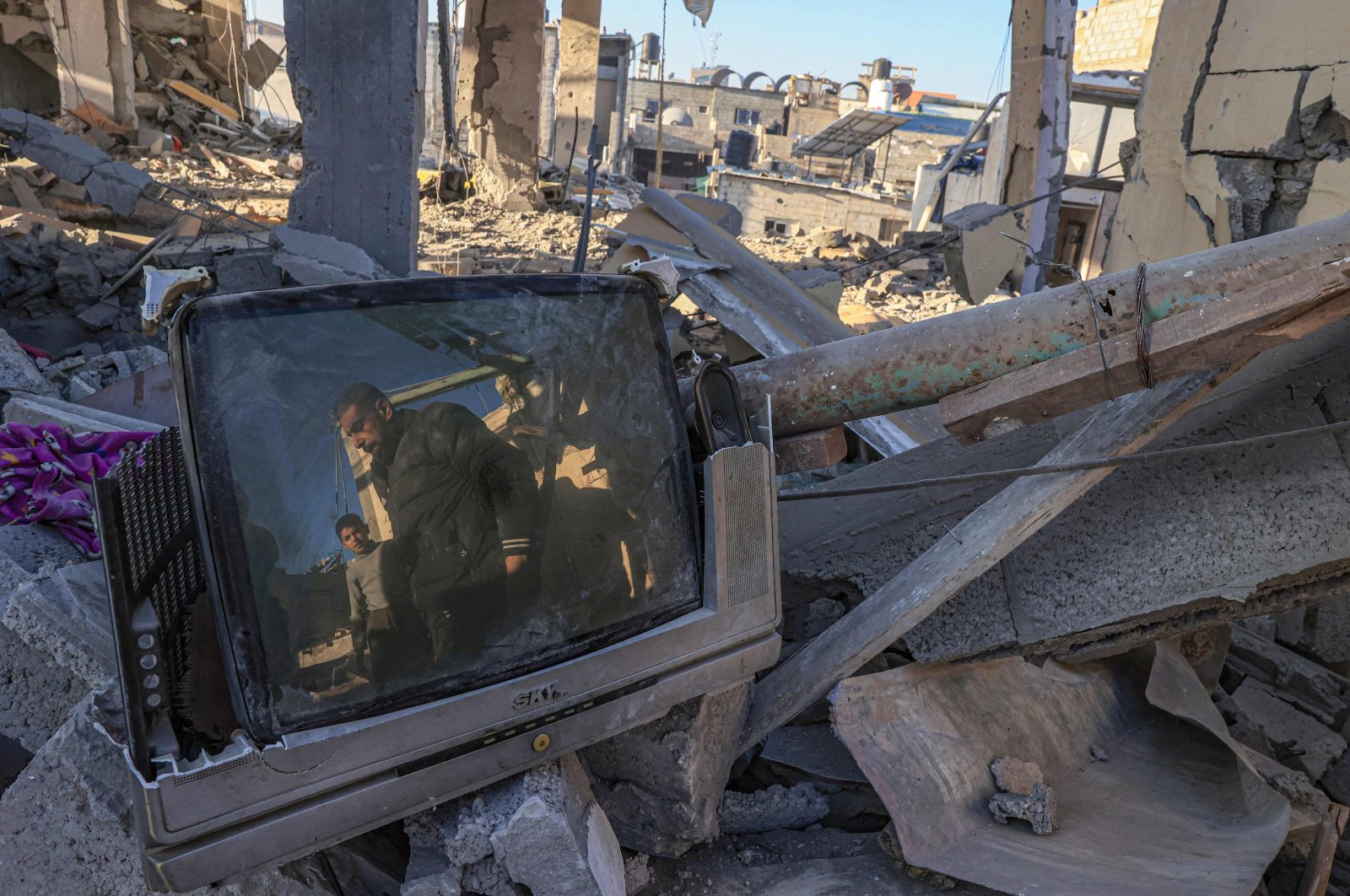 Palestinians are reflected on a damaged TV screen while searching the rubble of a building following Israeli bombardment, Rafah, southern Gaza Strip, Palestine, Dec. 26, 2023. (AFP Photo)