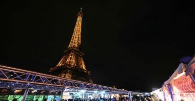 This photograph shows a view of visitors in a Christmas market with the Eiffel Tower monument in the background, in Paris, France, Dec. 23, 2023. (AFP Photo)