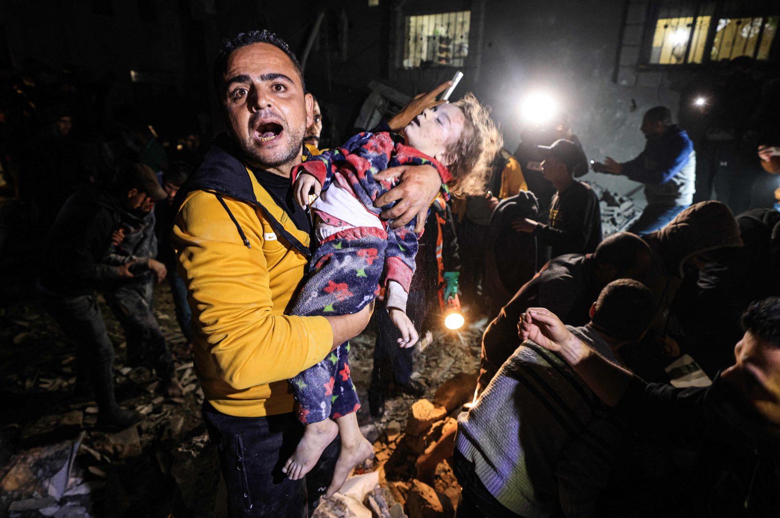 A man reacts as he holds a child removed from under the rubble of a building hit by an Israeli strike on Rafah in the southern Gaza Strip, Palestine, Dec. 28, 2023. (AFP Photo)