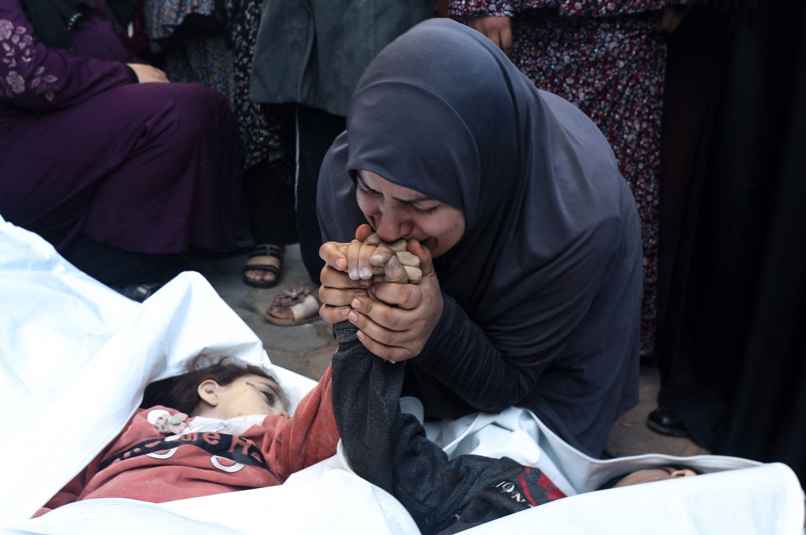 The mother of eight-year-old twins Ahmed and Jihan Nasser, who were killed during Israeli bombardment, kisses their hands as she mourns over their bodies at Al-Aqsa Hospital in Deir al-Balah in the central Gaza Strip Dec. 29, 2023. (AFP Photo)